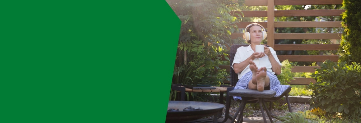 Eine Person entspannt mit Kopfhörern im Garten.